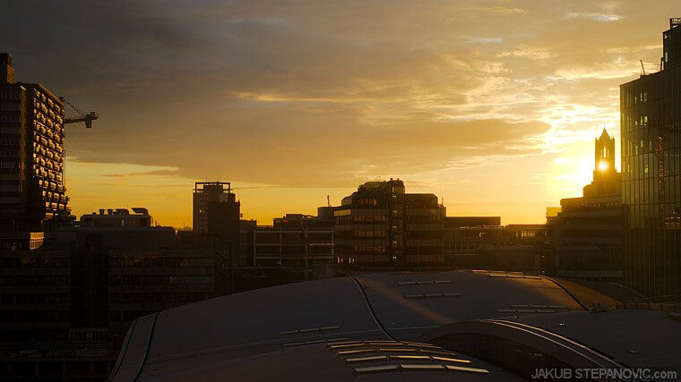 The rising sun intersects with the Gothic bell tower.